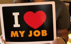 Assisted living staff member at Spring Gardens holds 'I love my job' sign. 